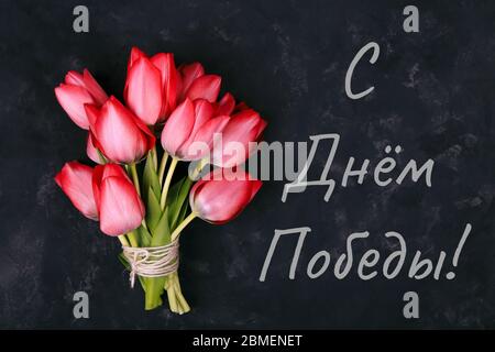 Text Happy Victory Day in Russian words. Bouquet of Pink Tulips on Black Background. Easter day background. Gift caard for victory day Stock Photo