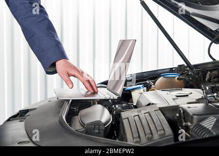 Car mechanic using computer in auto repair shop Stock Photo