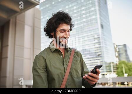 Handsome smiling young man in formal clothing using smartphone Stock Photo