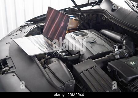 Laptop on a car in auto repair shop, Automobile mechanic repairman concept Stock Photo