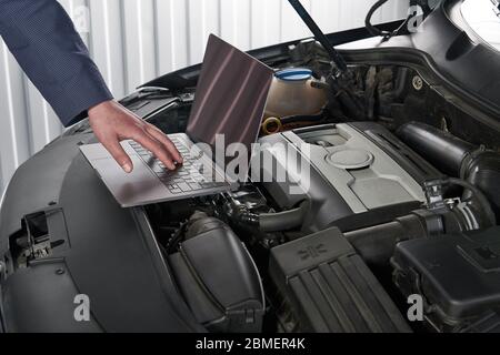 Car mechanic using computer in auto repair shop Stock Photo