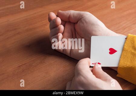 Man in yellow sweater shows an ace up his sleeve Stock Photo