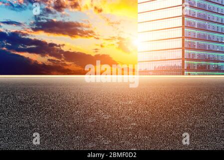Empty asphalt pavements and modern urban landmarks in the setting sun Stock Photo