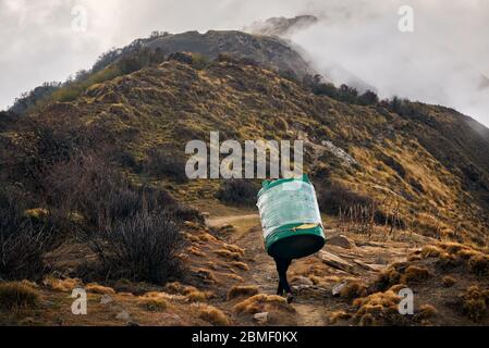 Nepal Porter Sherpa carrying big tank for water in the Himalayas Mountains, Annapurna trekking, Nepal Stock Photo