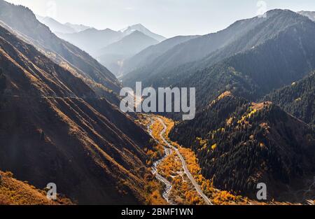 Aerial view of autumn forest near the road and river at the beautiful mountains in autumn time in Almaty, Kazakhstan Stock Photo
