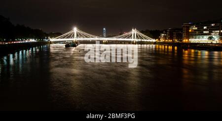London, England, UK - October 31, 2013: The ornate Albert Bridge is lit at night between Chelsea and Battersea on the River Thames in West London. Stock Photo