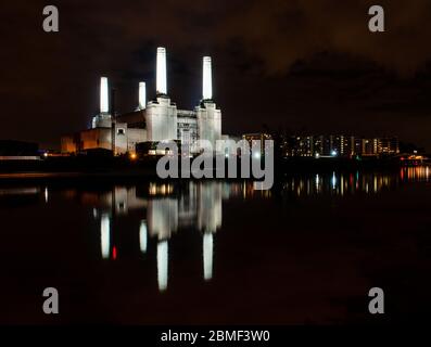 London, England, UK - October 8, 2013: The derelict shell of Battersea Power Station is lit at night on the side of the River Thames in West London. Stock Photo