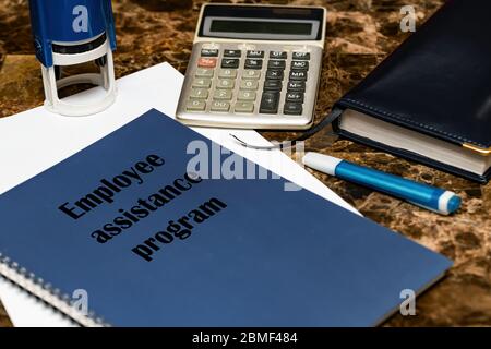 The EAP employee assistance program is written on a blue book lying on a marble Desk in the office among papers Stock Photo