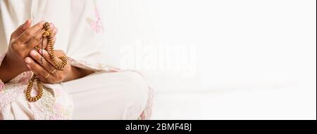 Muslim woman praying close up image of hands as she holds prayer beads,tasbih - religious, Islam, concept image with copy space for text Stock Photo
