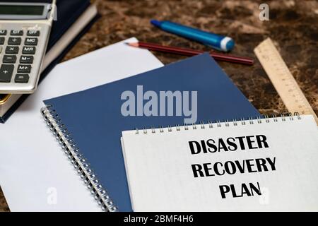 The text of the Disaster Recovery Plan is written on a white sheet lying on the office Desk. Stock Photo