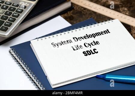 SDLC - System Development Life Cycle, acronym business concept. The text is written on a white sheet that lies on the office marble table. Stock Photo
