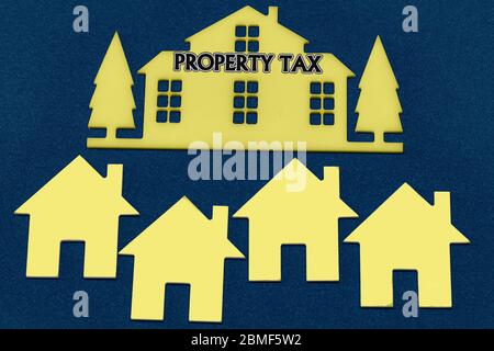 Miniature houses on a blue paint background and text Property Tax. Business, finance, saving money, property ladder or mortgage loan concept Stock Photo
