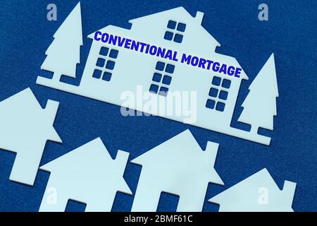 toy houses on a blue background. Text Conventional mortgage. The concept of profitable investment in real estate. Stock Photo
