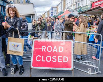 Road Closed sign with crowds of pedestrians at Portobello Market. Londoners & Tourists shopping & enjoying a day out. Portobello Road, Notting Hill Stock Photo
