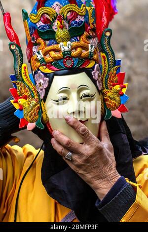 Di (Ground) opera dance performer putting on his mask. Mainly done by elderly men.  Anshun area, Guizhou province, China Stock Photo