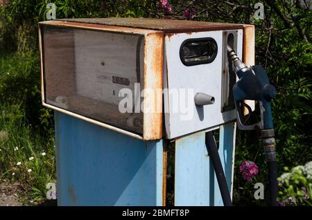 A rusty old-fashioned gas pump in front of an abandoned gas station Stock Photo