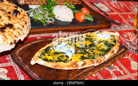 Traditional autyhentic turkish lunch or dinner: kebab with rice and vegetables, spinach and egg pide, pita flat bread and puff hot lavash or lavas hom Stock Photo