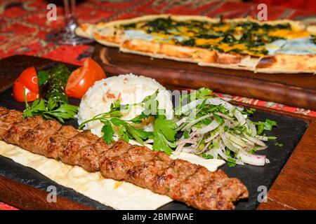 Traditional autyhentic turkish lunch or dinner: kebab with rice and vegetables, spinach and egg pide, pita flat bread and puff hot lavash or lavas hom Stock Photo