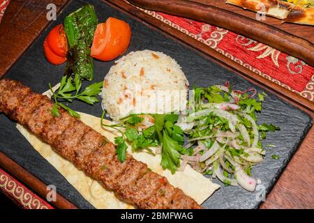 Traditional autyhentic turkish lunch or dinner: kebab with rice and vegetables, spinach and egg pide, pita flat bread and puff hot lavash or lavas hom Stock Photo