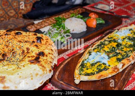 Traditional autyhentic turkish lunch or dinner: kebab with rice and vegetables, spinach and egg pide, pita flat bread and puff hot lavash or lavas hom Stock Photo