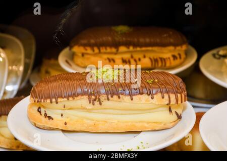 Traditional french dessert. Delicious eclairs with custard and chocolate icing for sweet tooth on a plate. Pastry products. Stock Photo