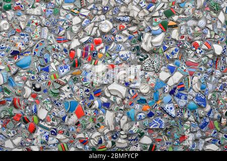 Close up of a wall, decorated with broken pieces of handmade ceramic pots. Very colorful texture and background. Stock Photo