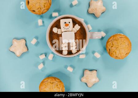 A marshmallow snowman in hot chocolate, surrounded by biscuits and mince pies Stock Photo