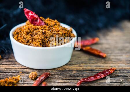 Spicy dried fishes chili paste with white ceramic container on wood background Stock Photo