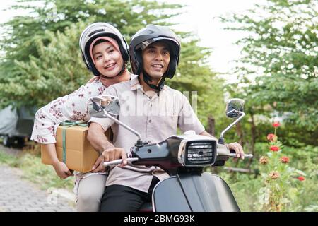 Muslim couple riding a motorcycle for travel in eid mubarak Stock Photo