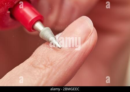 Woman filings nails with electric nail file at home. Electric Nail File Manicure Pedicure Drill. Manicure at home. Closeup, selective focus Stock Photo