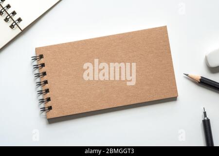 Close up. Kraft Paper Cover Spiral Notebook with Pencil, Eraser and Open Notebook on white Background. Empty Space for Your Text. Stock Photo