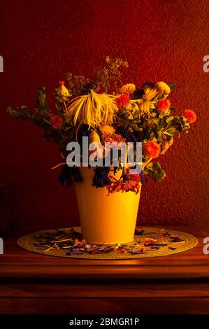 Wilting  flowers including mums,chrysanthemums,carnations in yellow bucket Stock Photo