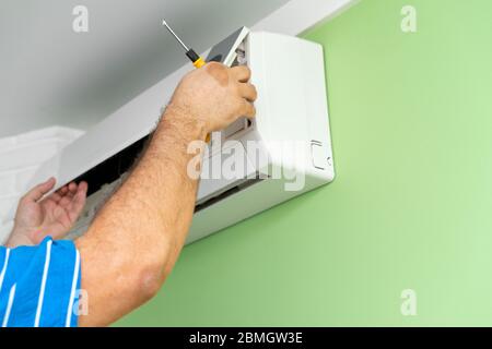 Male technician repairing and reading air conditioners. Opening the lid and repair diagnostics Stock Photo