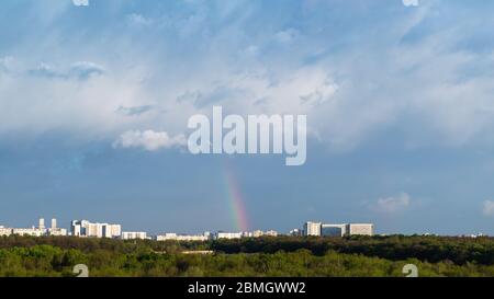 blue thunderclouds and rainbow over city on sunny spring day Stock Photo