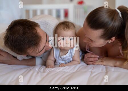 Couple snuggle with their infant daughter on the couch Stock Photo