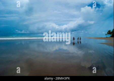 Three Walking Along a Beach in a Storm Reflecting Stock Photo