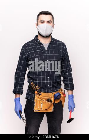 Young repairman in casualwear, protective mask and gloves holding diy handtools while going to repair furniture or house Stock Photo