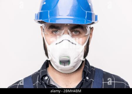 Head of contemporary engineer in hardhat and protective mask and eyeglasses standing in front of camera and looking at you Stock Photo