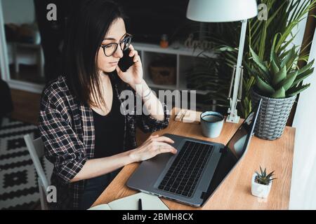 Young woman talking on the phone in her home office. Work from home concept Stock Photo