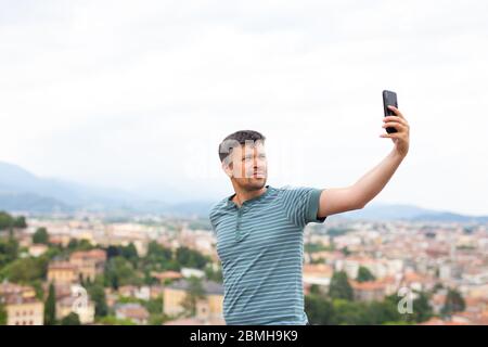 Man taking photos and selfie with mobile smart phone in a town. Travel concept. Traveller. Summer vacations.  Stock Photo