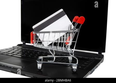 A credit card in a miniature shopping cart on a laptop. E-commerce and online shopping concept. Stock Photo