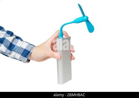 Female hand turns on a portable usb fan connected to a silver power bank. Closeup shot, isolated on white. Stock Photo