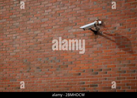 CCTV security surveillance camera mounted on a red brick wall. Stock Photo