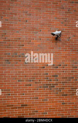 CCTV security surveillance camera mounted on a red brick wall. Stock Photo