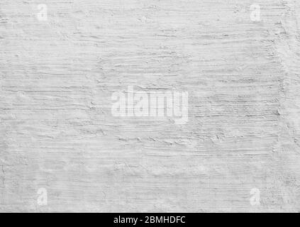 Plastered and rough concrete or stone wall painted in white or light gray, hand made stucco texture. Full frame textured background in black and white. Stock Photo
