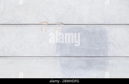Front view of a plastered and damaged gray stone wall with stains from graffiti removal. Abstract high resolution full frame textured background. Stock Photo