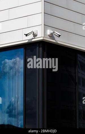 Two CCTV security surveillance cameras mounted on a corner of a modern office building. Stock Photo