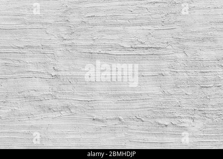 Close-up of a plastered & rough concrete wall painted in white or light gray, hand made stucco texture. Full frame textured background in black&white. Stock Photo
