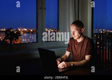Man working on laptop from home at night. Blue screen light Stock Photo