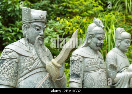 Standing stone statue with weapon at the buddhist Temple of Ten Thousand Buddhas in Pai Tau, New Territories, Hong Kong Stock Photo